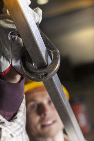 young metalworker hooks a steel tube to liftの写真素材