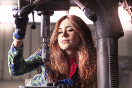 portrait of pretty girl at work on industrial drilling machine