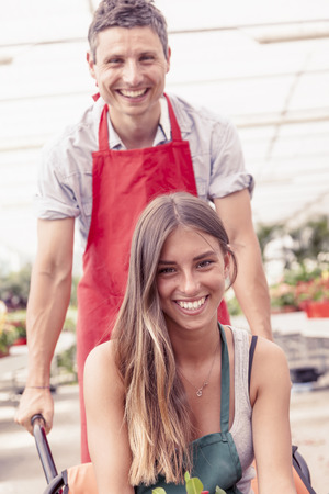 sellers couple have fun pushing the wheelbarrow in a greenhouseの写真素材