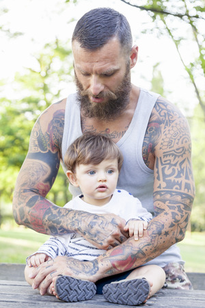 tattooed father have fun with his son in the parkの写真素材