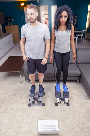 young couple he trains with the step machine at homeの写真素材