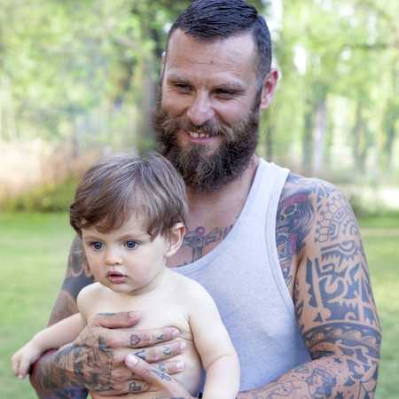tattooed father have fun with his son in the parkの写真素材