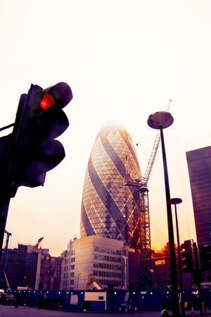 view of gherkin tower in London photographed from below a traffic light on a vintage warm color filtered lookの写真素材