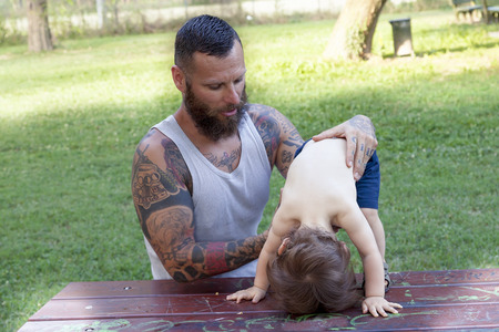 tattooed father have fun with his son in the parkの写真素材