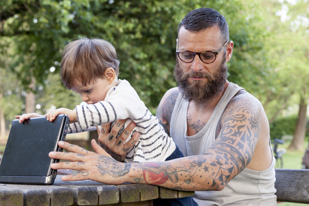 tattooed dad have fun with his son and laptopの写真素材
