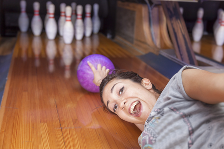 young woman sliding down a bowling alleyの写真素材