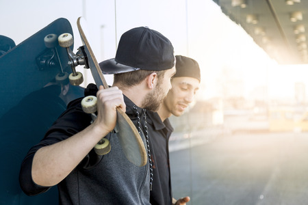 couple of happy young skateboarders relaxes you in front of a stained glass windowの写真素材
