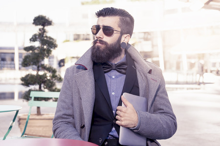 young hipster businessman consults his laptop in the heart of cityの写真素材