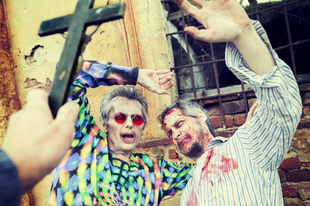 exorcism with a crucifix on two zombies in the cemeteryの写真素材