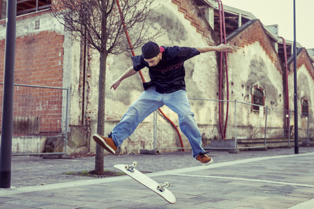 young boy jumping with skateboard in outskirt streetの写真素材