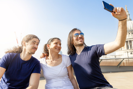 group of three young friends take a selfie on a london terraceの写真素材