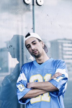 a rap singer is reflected in a blue mirror on the outskirts