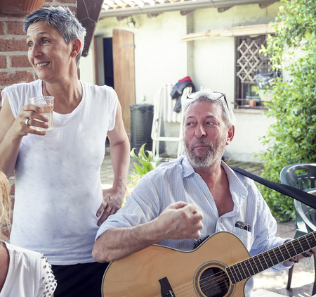 happy people eat and play guitar at party in the countrysideの写真素材