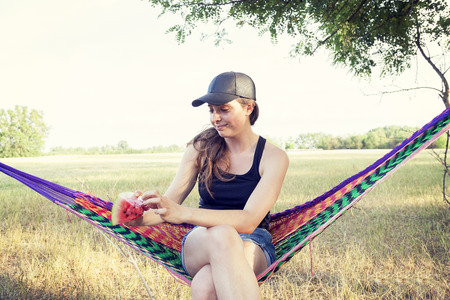 portrait of young pretty woman eating a slice of watermelon outdoorsの写真素材
