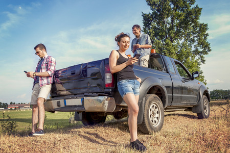 group of friends playing on smart phone in the countryside during a break