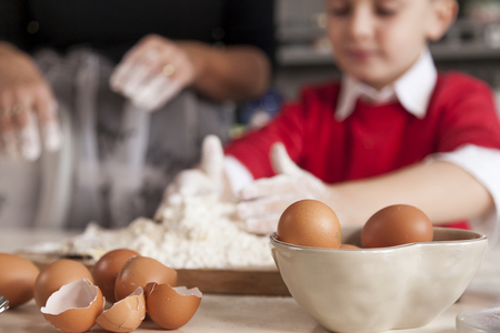 Little boy having fun and prepare the dough for cookies with eggs and flour in home cookingの写真素材