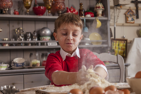 Little boy having fun and prepare the dough for cookies with eggs and flour in home cookingの写真素材