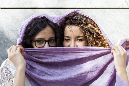 couple of pretty young woman in the center of a capital city having fun with a scarf