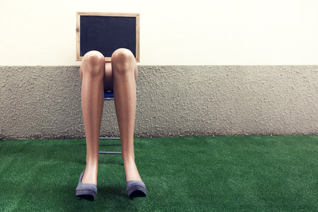 dummy legs resting on a chair over a synthetic grass carpetの写真素材