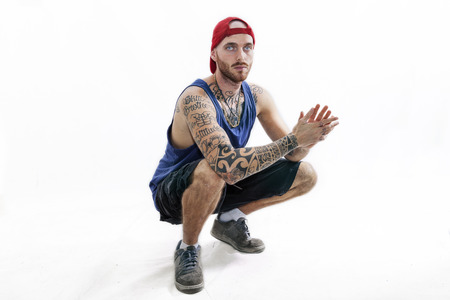sitting tattooed rap singer posing in studio with expressive position on a white background