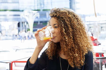 portrait of beautiful tourist girl sitting outdoor at the coffee bar of a big cityの写真素材