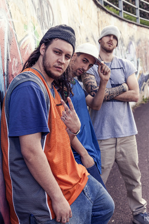 three rap singers in a subway with graffiti in the background posing in aggressive styleの写真素材