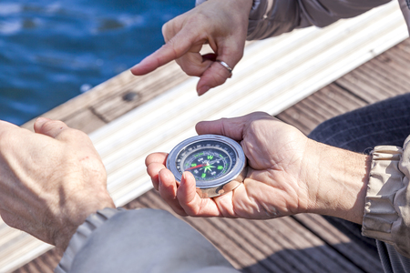 beautiful mature couple sitting on the dock looks at compass on a winter dayの写真素材
