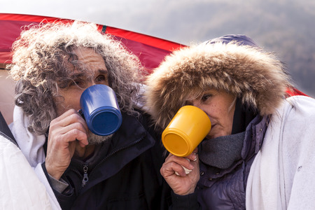 beautiful mature couple relaxing and drinking hot coffee on the lake in a winter dayの写真素材