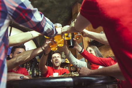 group of people celebrating in a pub drinking beer and eating snacksの写真素材