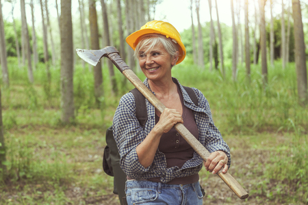 experienced female lumberjack while visiting a forest before cutting some treesの写真素材