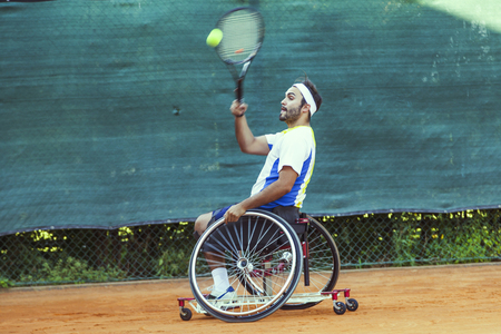disabled tennis player hits the ball forehand during a match outdoorの写真素材