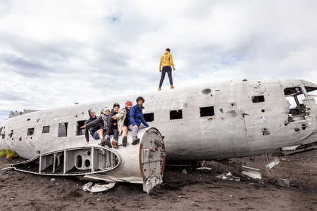 group of friends having fun walking over the wreck of a plane in Iceland