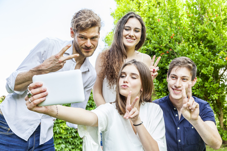 group of young friends take a selfie hugged together outdoors with funny facesの写真素材
