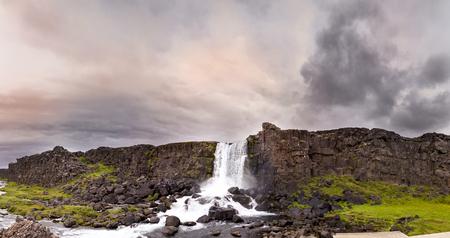 panoramic view of majestic waterfall in Pingvellir natural volcanic park under dramatic sky in Icelandの写真素材