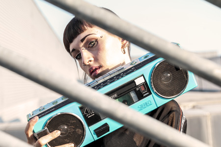 young female singer rap caucasian tattooed posing with a stereo radio on a metallic ladderの写真素材