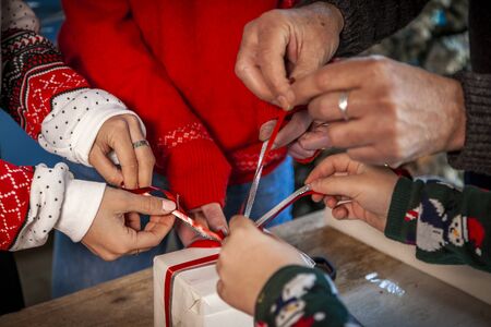 detail of family hands preparing christmas gifts on table at home