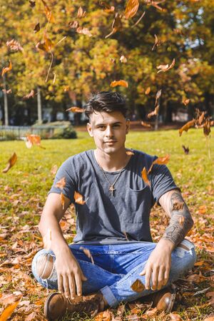 young adult of the millennial generation relaxes among the leaves of a public park. autumn vacation conceptの写真素材