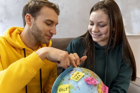 young couple is planning the next trip by choosing the destination on the globe map. concept of vacation in the worldの写真素材