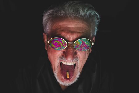 portrait of mature man in front of computer monitor is taking a medicine pill. The screen image...