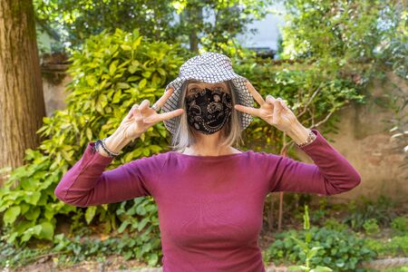pretty adult woman with mask looks into camera during quarantine due to pandemic covid-19 coronavirusの写真素材