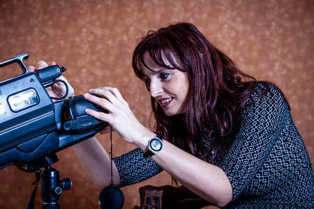 beautiful woman sitting in a photo studio playing with a vintage cameraの写真素材
