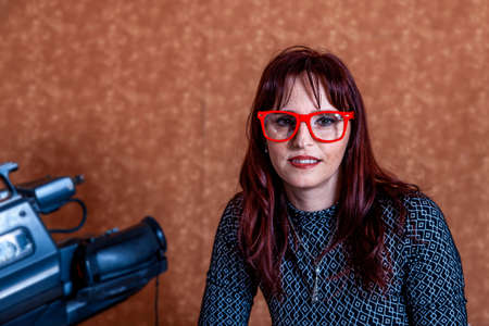 beautiful woman sitting in a photo studio playing with a vintage cameraの写真素材