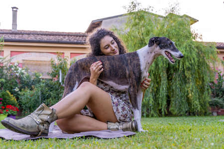 portrait of young woman with her hunting dog in the home gardenの写真素材