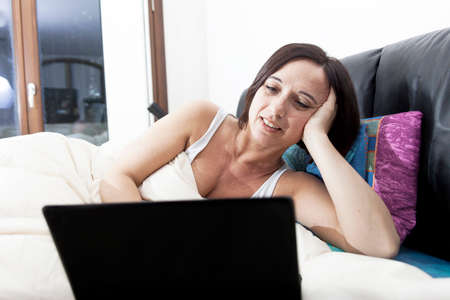 young woman working at computer at home in her bed