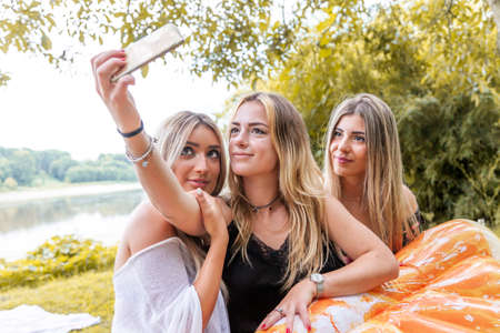 female millennial girlfriends taking a selfie outdoors on the river. youth summer vacation concept