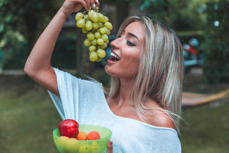 young pretty woman is eating fresh fruit on vacation. healthy life conceptの写真素材