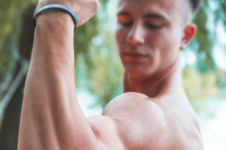 young muscular adult showing off his biceps outdoors. healthy life conceptの写真素材