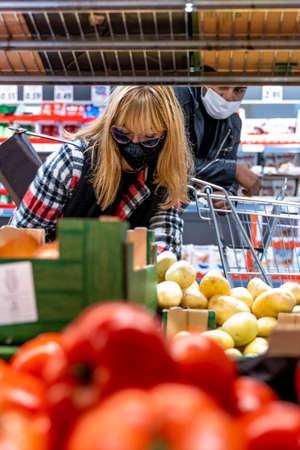 multi-ethnic couple is shopping in a supermarket wearing face masks during the coronavirus emergency periodの写真素材