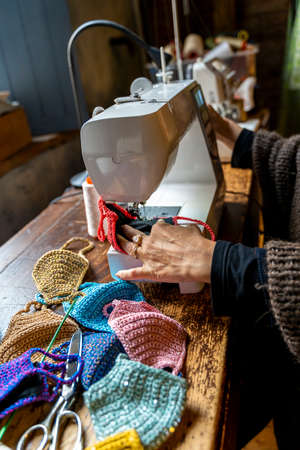 seamstress is making colored fabric face masks in her workshop