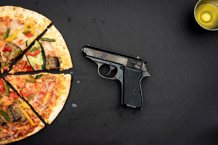 tasty grilled vegetable pizza near a gun on black background. top viewの写真素材
